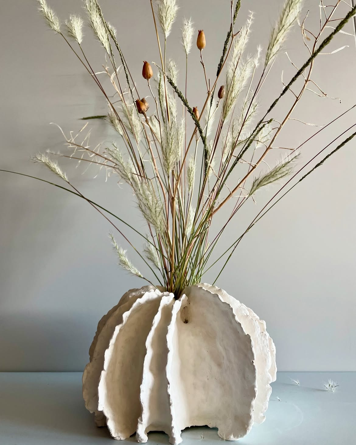 Vase blanc à corolles de pulpe avec un bouquet de fleurs séchées